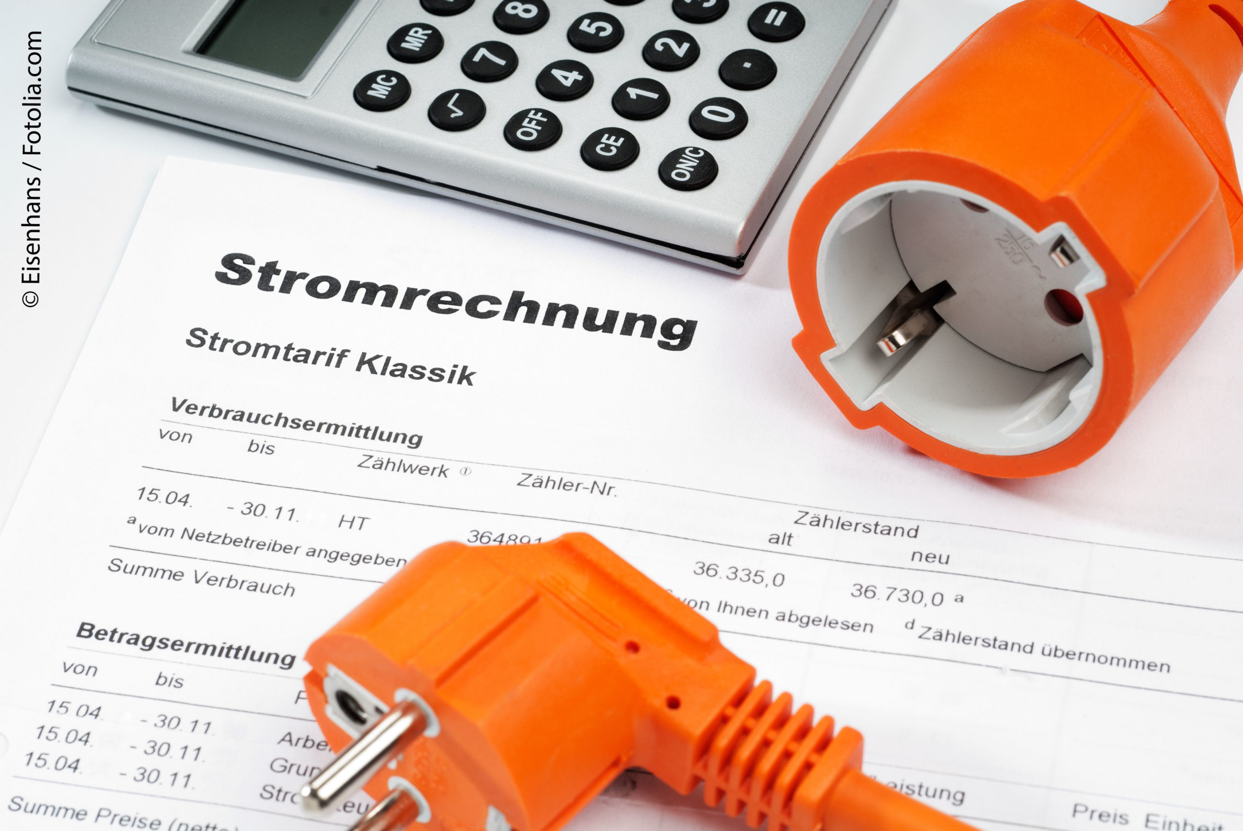 Stecker und Taschenrechner liegen auf einer Rechnung