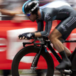 Radfahrer in schwarzer Ausrüstung rast bei einer Veranstaltung im Freien an einem Wien Energie Banner vorbei.