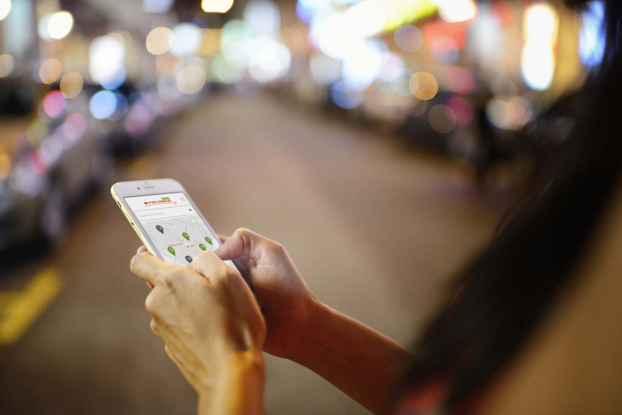 Frau verwendet Wien Energie E-Tanke App auf einem Smartphone, Close Up