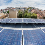 Solarmodule auf dem Dach der Berufsschule Apollogasse. Bewölkter blauer Himmel im Hintergrund.