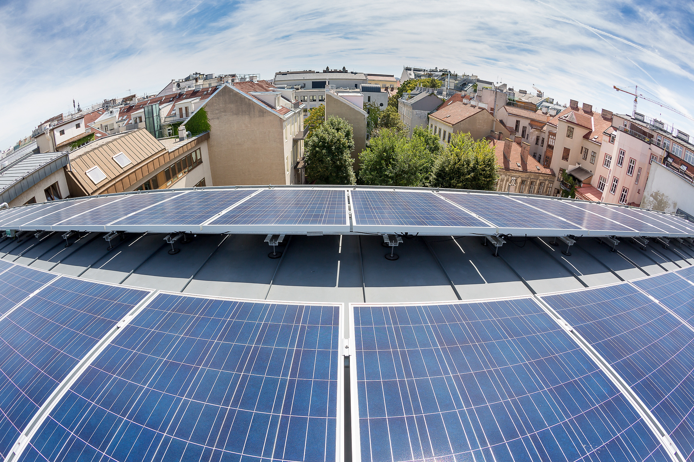 Solarmodule auf dem Dach der Berufsschule Apollogasse. Bewölkter blauer Himmel im Hintergrund.