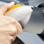 Eine Hand steckt ein Ladekabel in die Steckdose eines Elektrofahrzeugs.