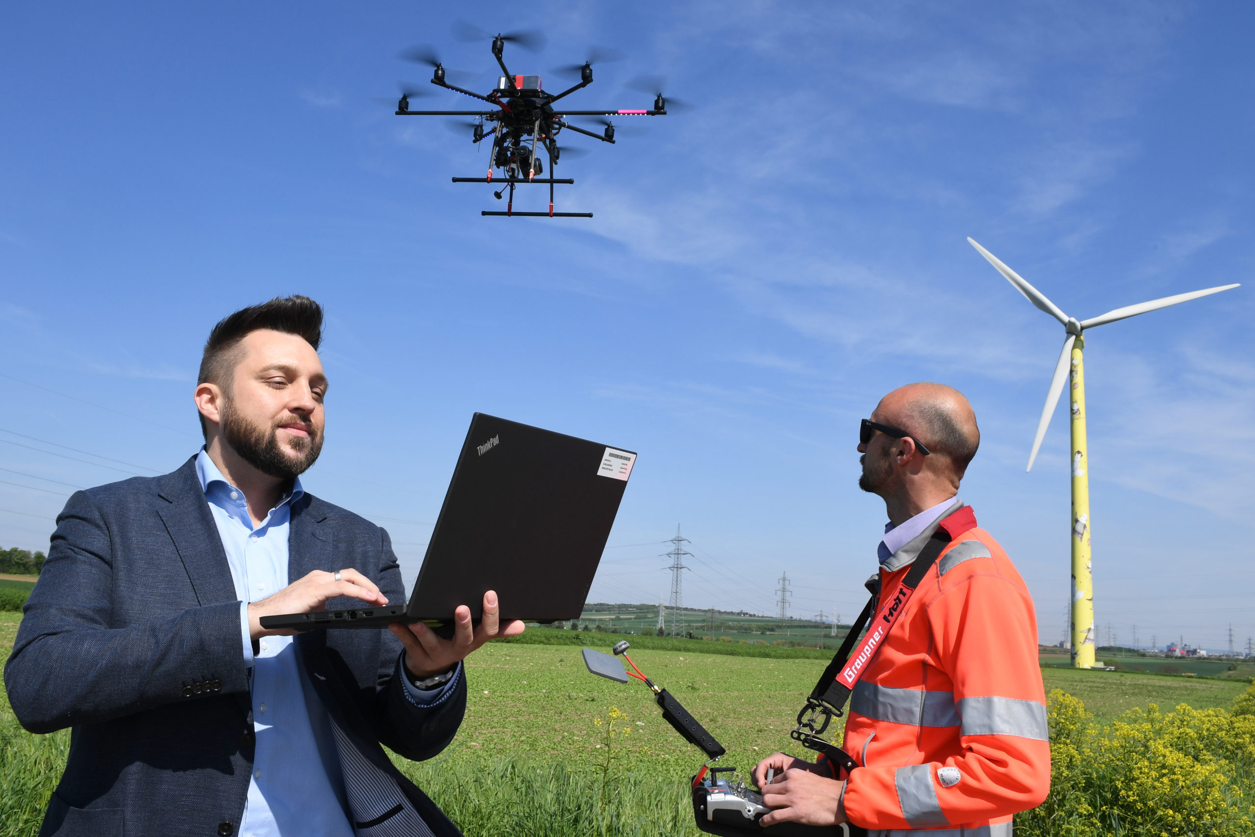 Wien Energie Mitarbeiter steuert eine Drohne per Laptop um die Windrad-Wartung durchzuführen.