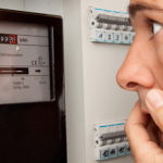 Mann schaut auf den Stand des Stromzählers und erschreckt sich.