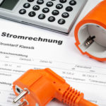 Stecker und Taschenrechner liegen auf einer Rechnung