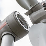 Rotorblätter werden mit einem Kran auf den Turm der Windkraftanlage gehoben.