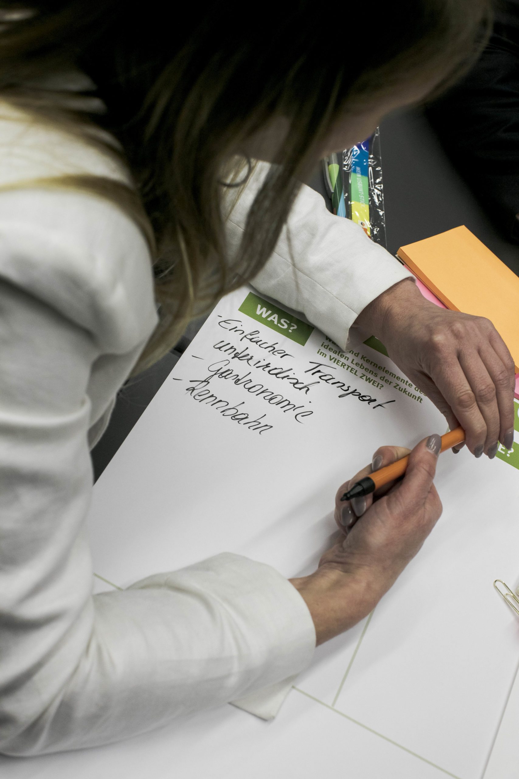 Frau notiert Informationen auf einem Blatt Papier.