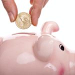 rosarotes Sparschwein wird mit Münzen gefüttert.