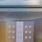 Milchglastür eines Kühlschranks mit Symbolen und sichtbaren Lebensmitteln im Inneren.