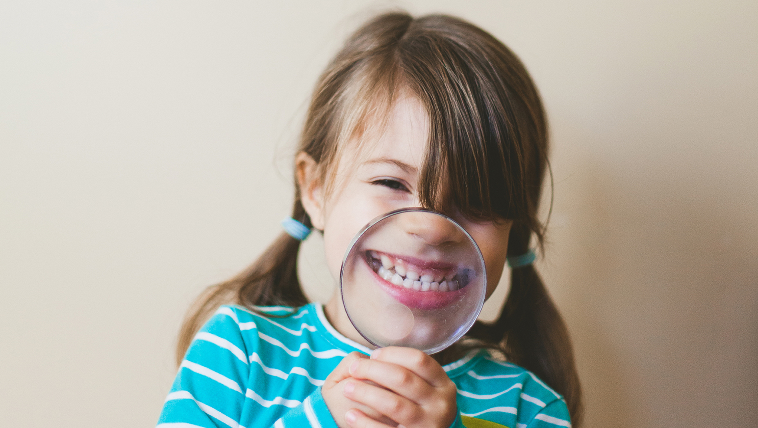 maedchen_grinst_durch_eine_lupe
