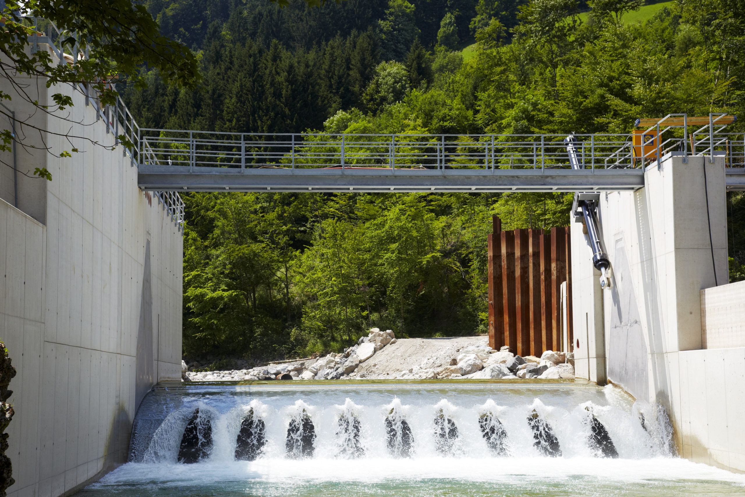 Das Wasserkraftwerk Opponitz umgeben von üppigem Grün und Bäumen unter einem klaren Himmel.