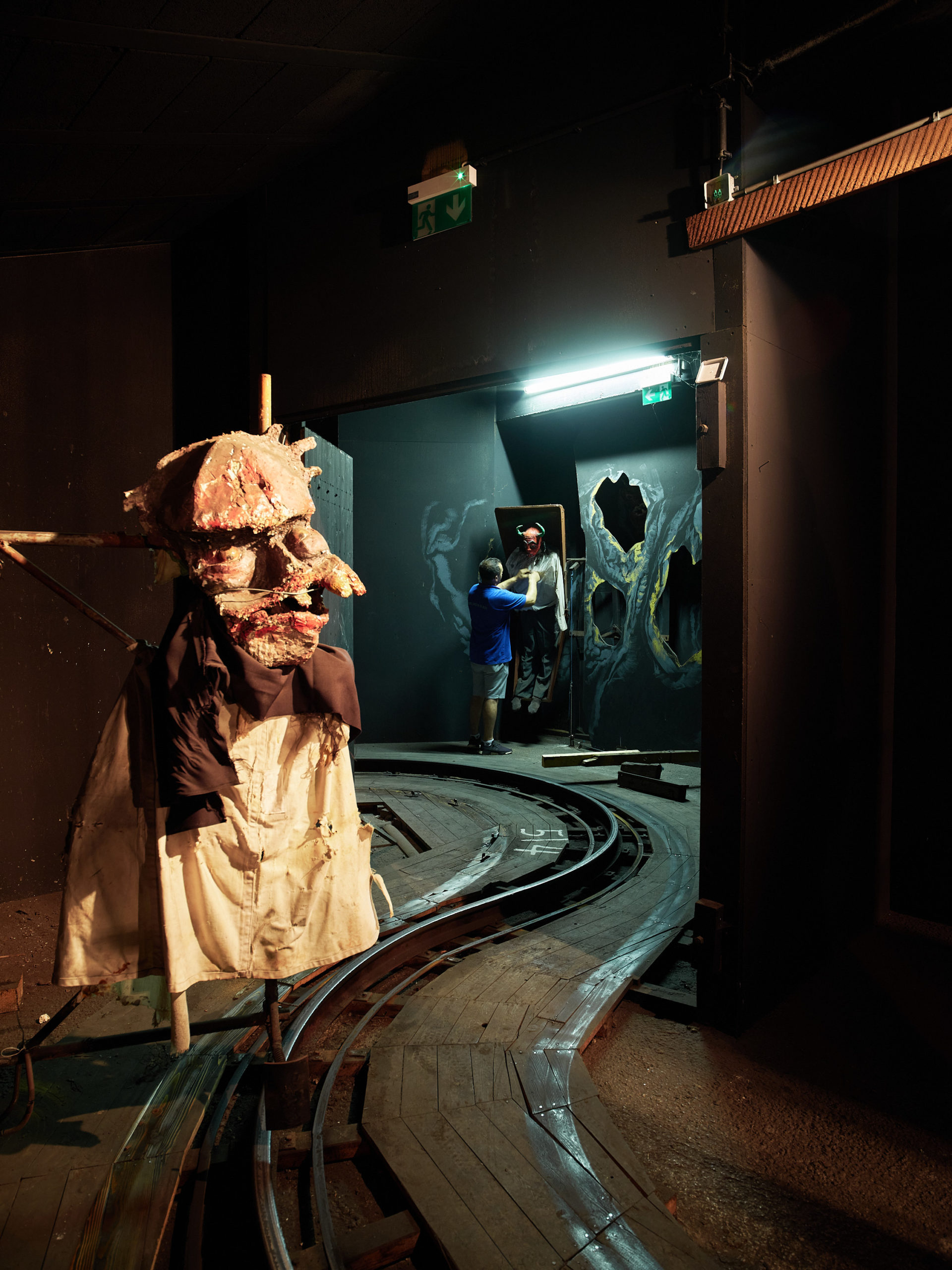 Dunkler, unheimlicher Raum in der Geisterbahn im Wiener Prater: Schienen liegen auf dem Boden, und eine gruselige Gestalt steht in der Ecke.
