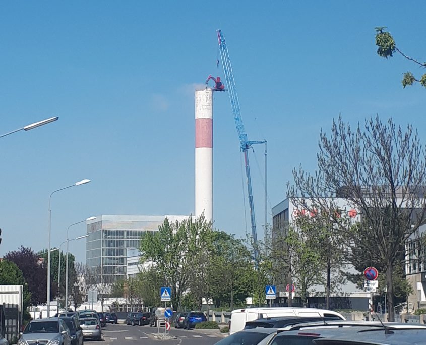 Ein Kran steht neben dem hohen Schornstein des Fernheizwerks Kagran.