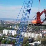 Bagger hängt an einem Kran um den 86 Meter hohen Schornstein des Fernheizwerks Kagran abzureißen.