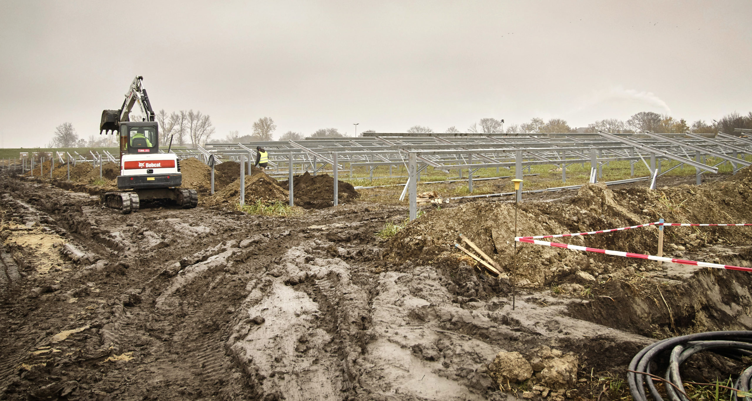 Beginn der Bauarbeiten für die Photovoltaikanlage Schafflerhofstraße. Bagger arbeitet auf dem Feld.