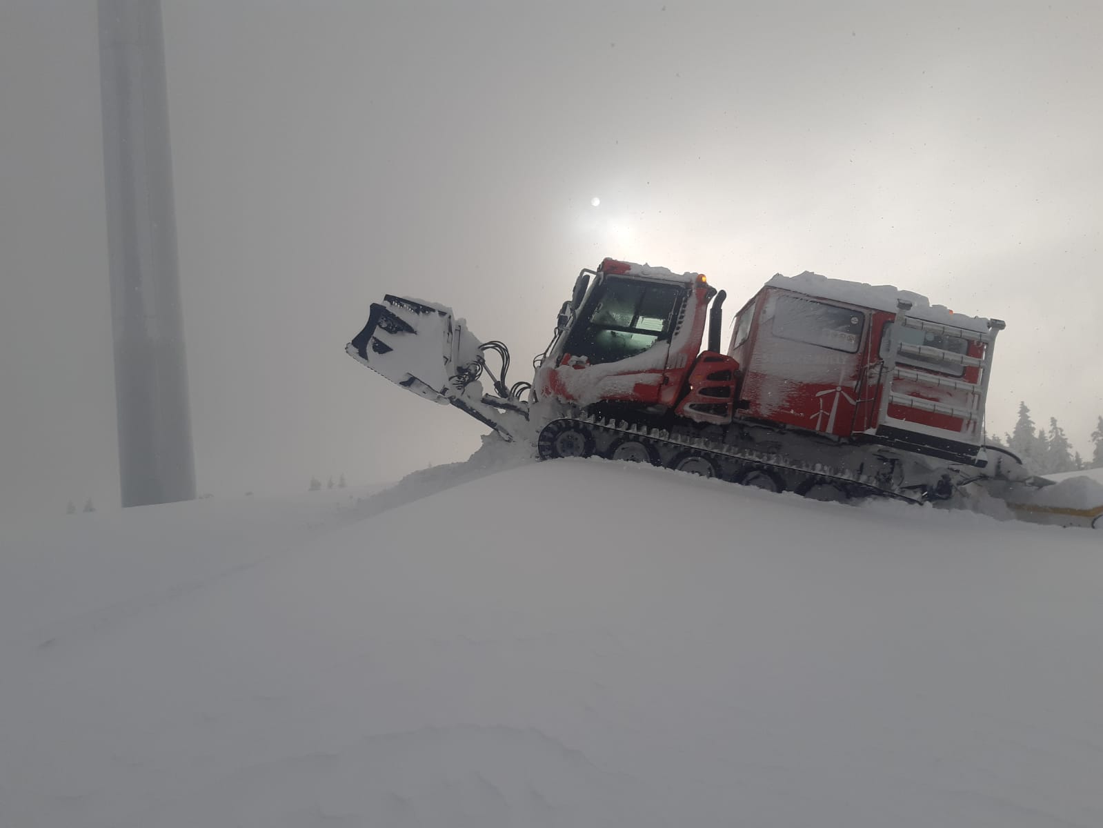 Pistenraupe bei Schnee, im Nebel, beim Windpark Steinriegel.
