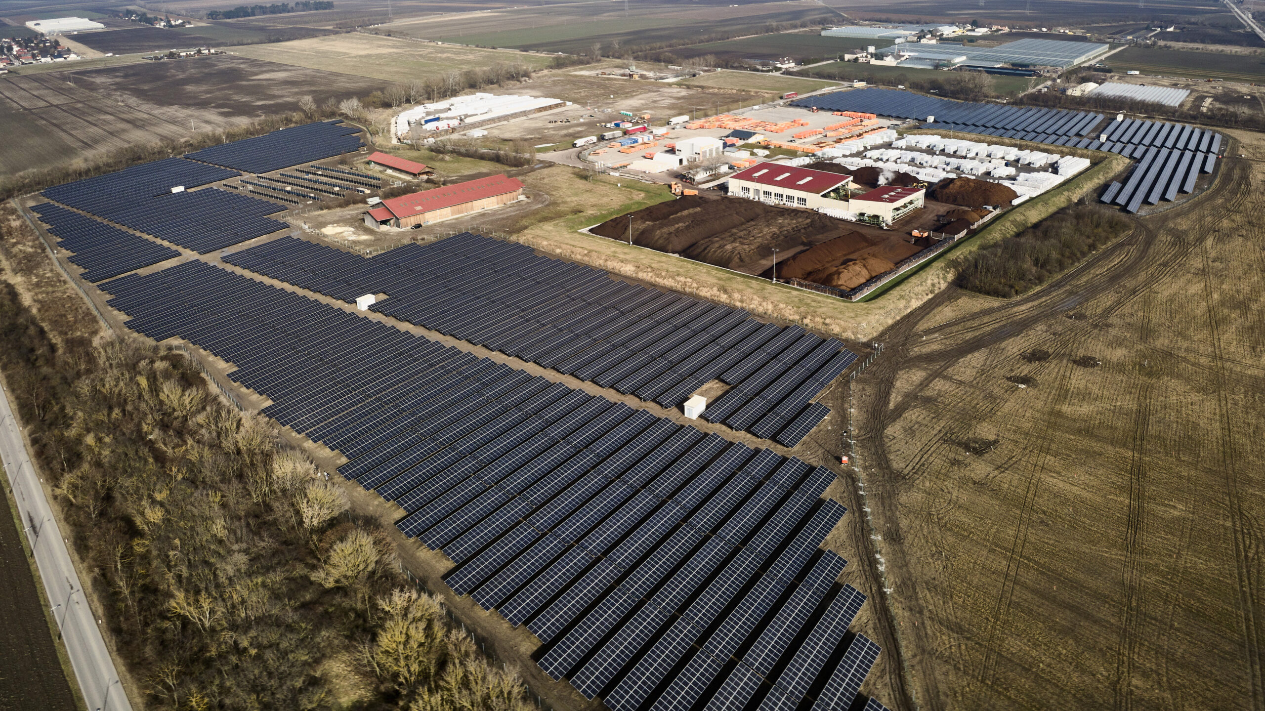 Luftaufnahme der großen Photovoltaikanlage Schafflerhofstraße mit Reihen von Solarmodulen in der Nähe von Gebäuden und Feldern in der Donaustadt.