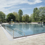 An einem sonnigen Tag liegt das leere Freibad im Gänsehäufel Bad friedlich umgeben von Bäumen.