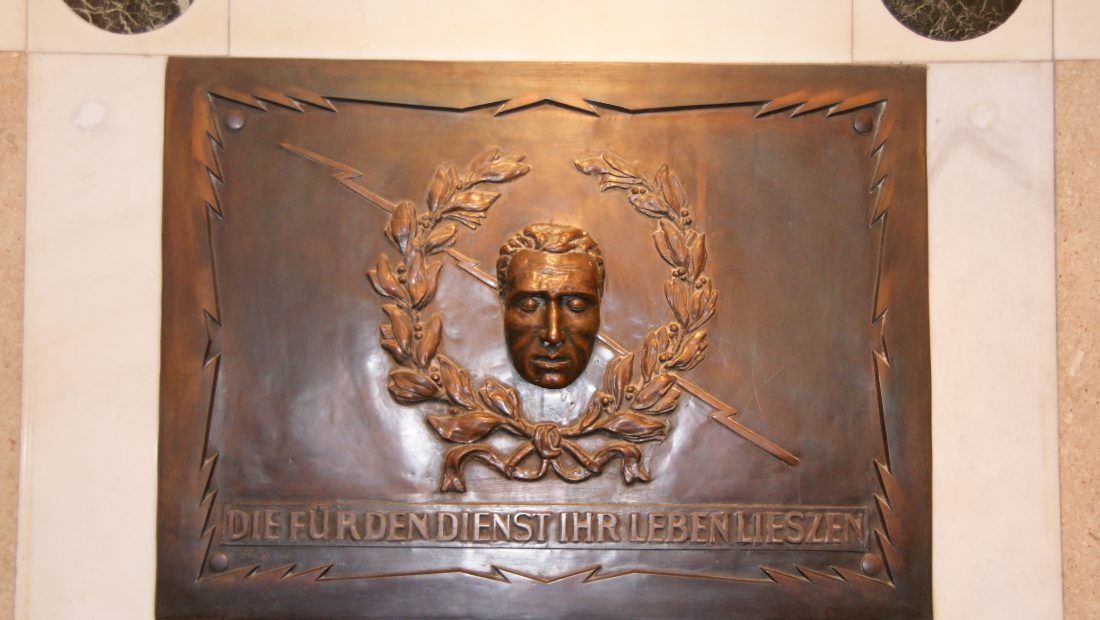 Bronzerelief mit Gesicht im Kranz und deutscher Inschrift darunter. Ehemaliger Standort Mariannengasse Kupferportrait.