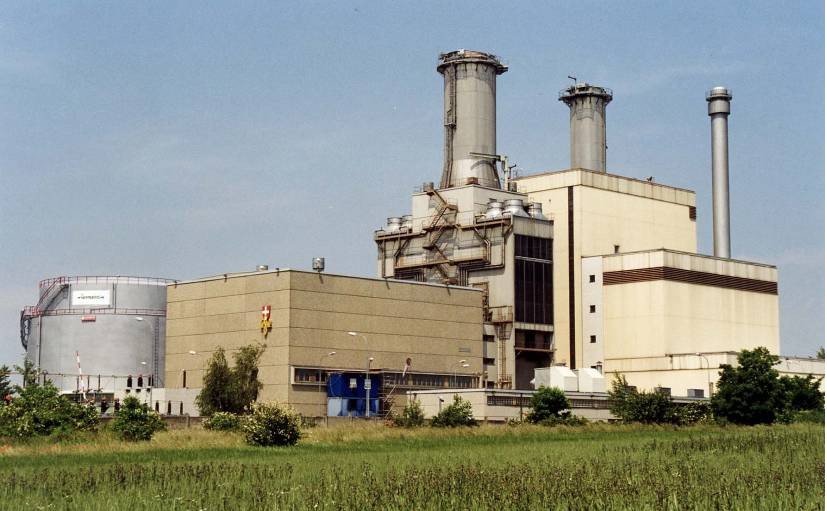 Kraftwerk Leopoldau mit hohen Schornsteinen, umgeben von Grün unter einem klaren Himmel.