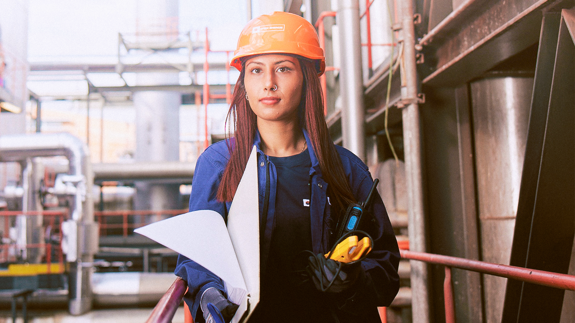 Frau in Kraftwerk mit Schutzhelm und Unterlagen