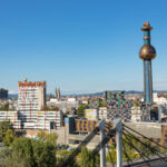 Luftaufnahme der Skyline von Wien mit farbenfrohen Gebäuden und dem markanten Hundertwasserturm der Wien Energie Spittelau.