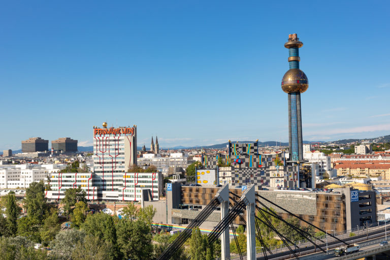 Luftaufnahme der Skyline von Wien mit farbenfrohen Gebäuden und dem markanten Hundertwasserturm der Wien Energie Spittelau.