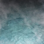 Dampfende, türkisfarbene Wasseroberfläche mit aufsteigendem Nebel, der eine heitere und ätherische Atmosphäre schafft.