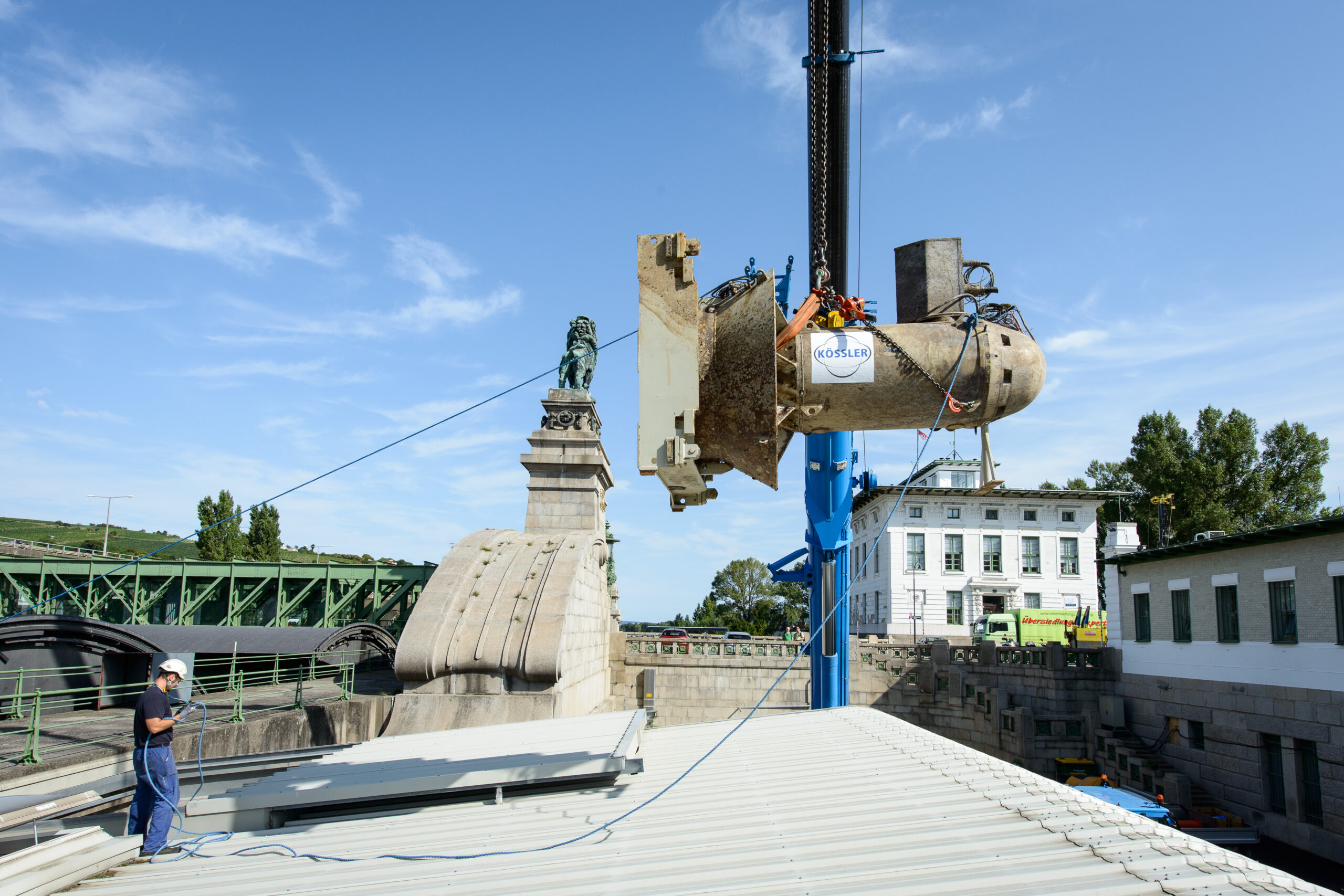 Ein Kran hebt die Hydro-Matrixturbinen in das Kraftwerk Nussdorf. Im Hintergrund ist Wien bei klaren Himmel zu sehen.