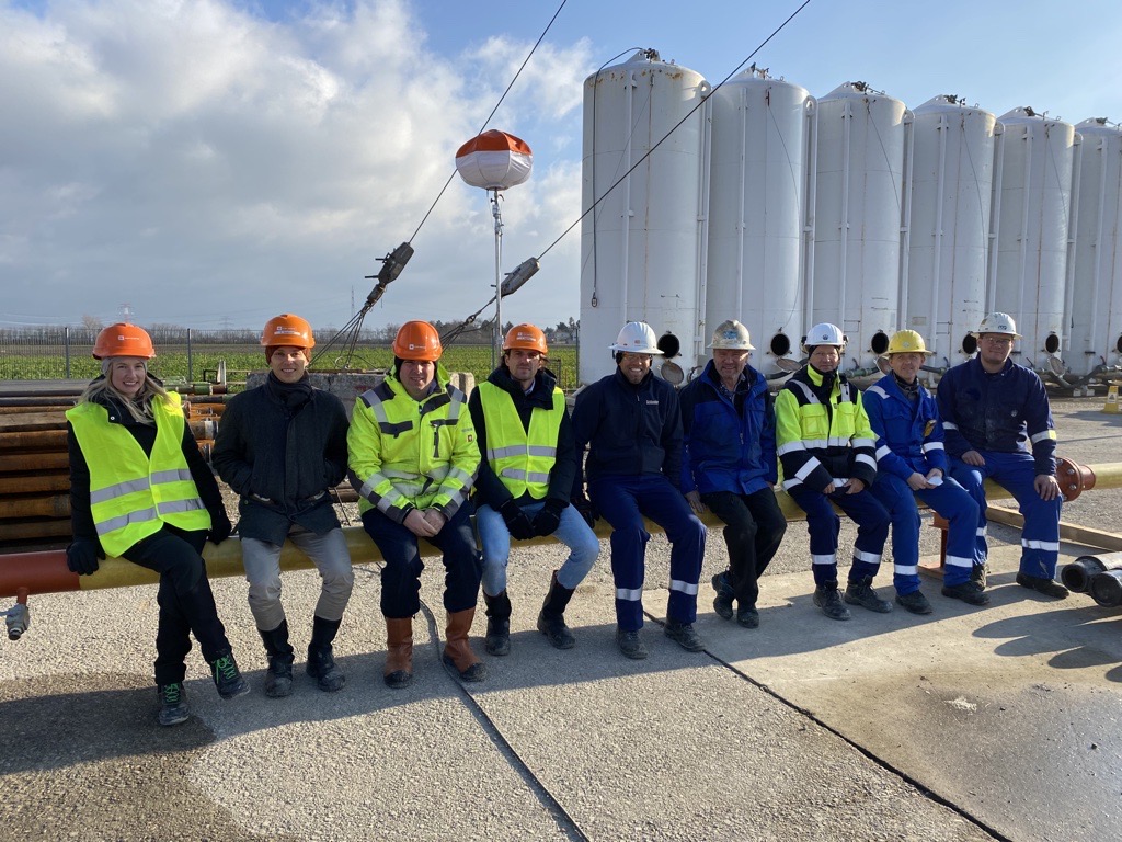 Helene mit Kollegen in Arbeitskleidung sitzt vor dem Kraftwerk