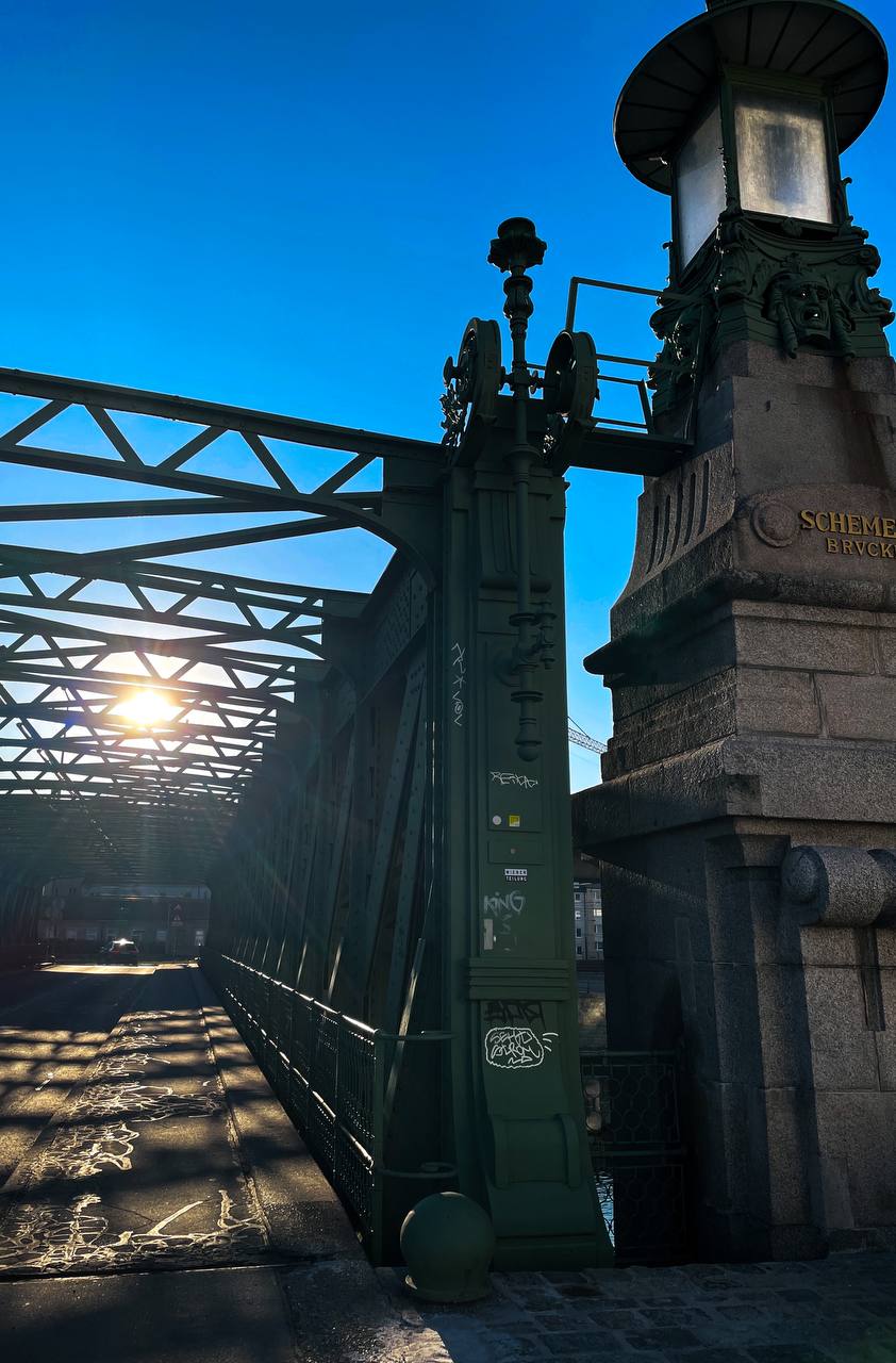 Sonnenlicht scheint durch die Stahlträger der Schemerlbrücke in Nußdorf, die unter einem klaren blauen Himmel steht.