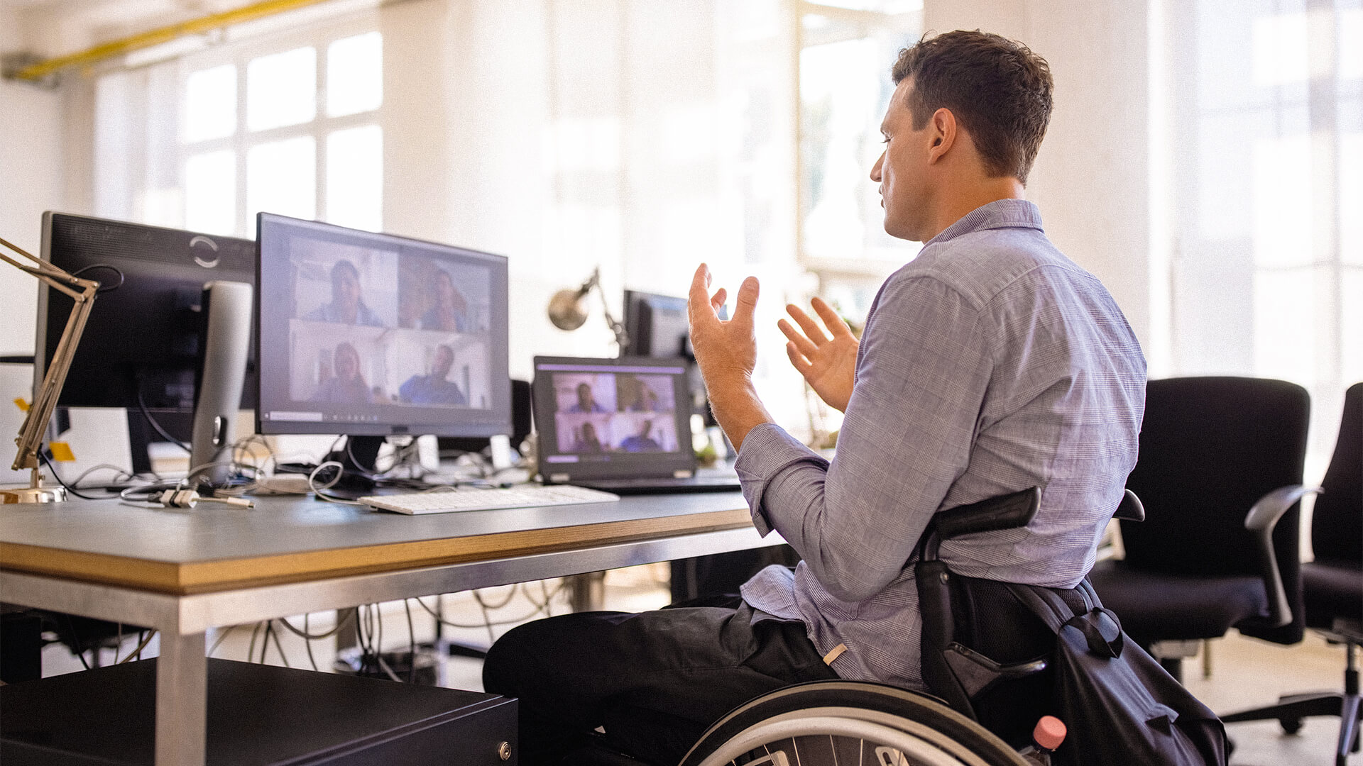 Junger Mann sitzt im Rollstuhl und nimmt per Videochat an einem Meeting teil.