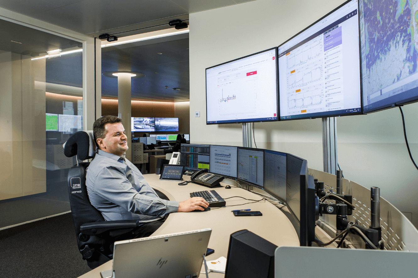 Person am Schreibtisch mit mehreren Monitoren in einer modernen, hochtechnologischen Büroumgebung - der Warte in Erdberg.