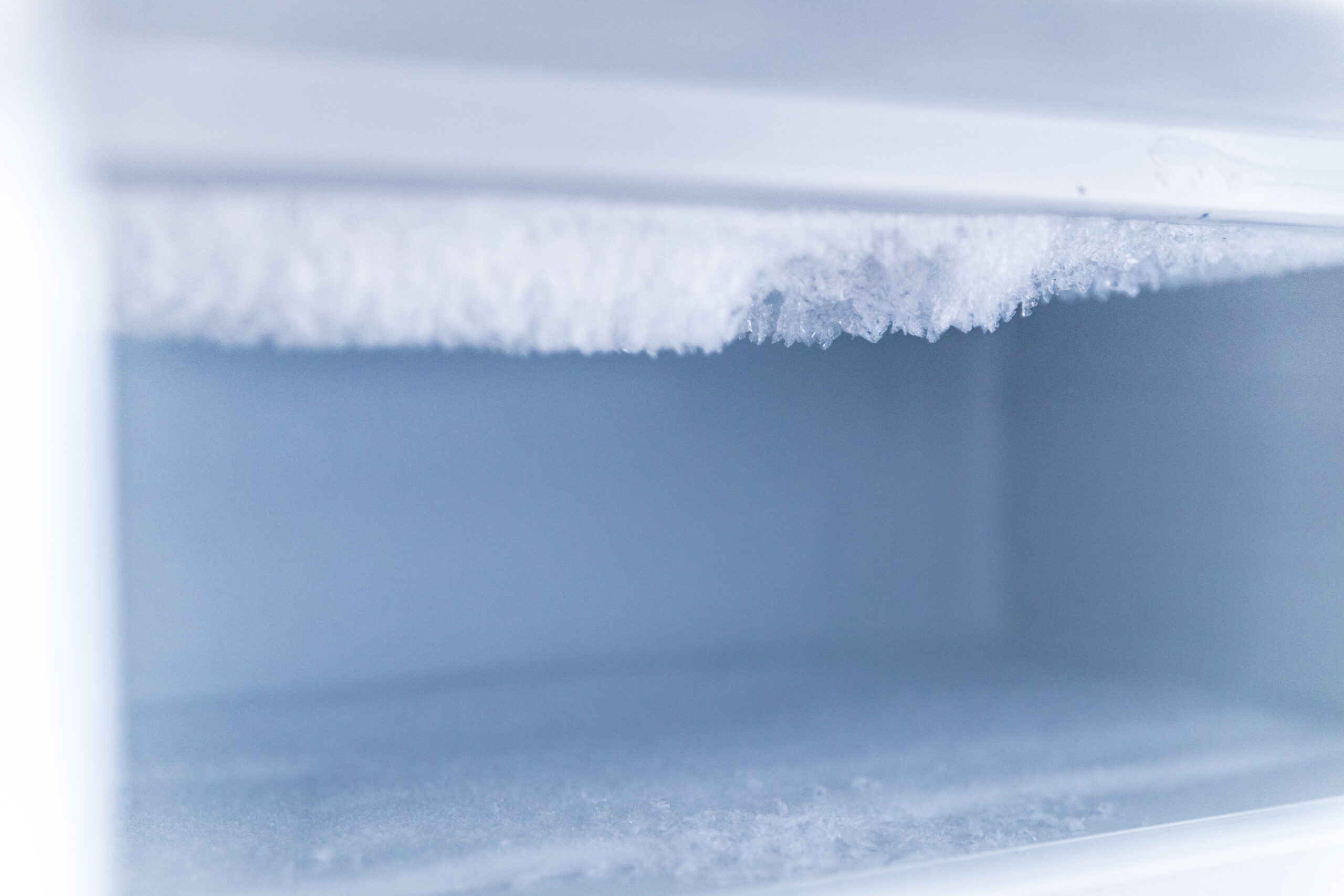 Nahaufnahme der Frostbildung in einem leeren Gefrierfach.