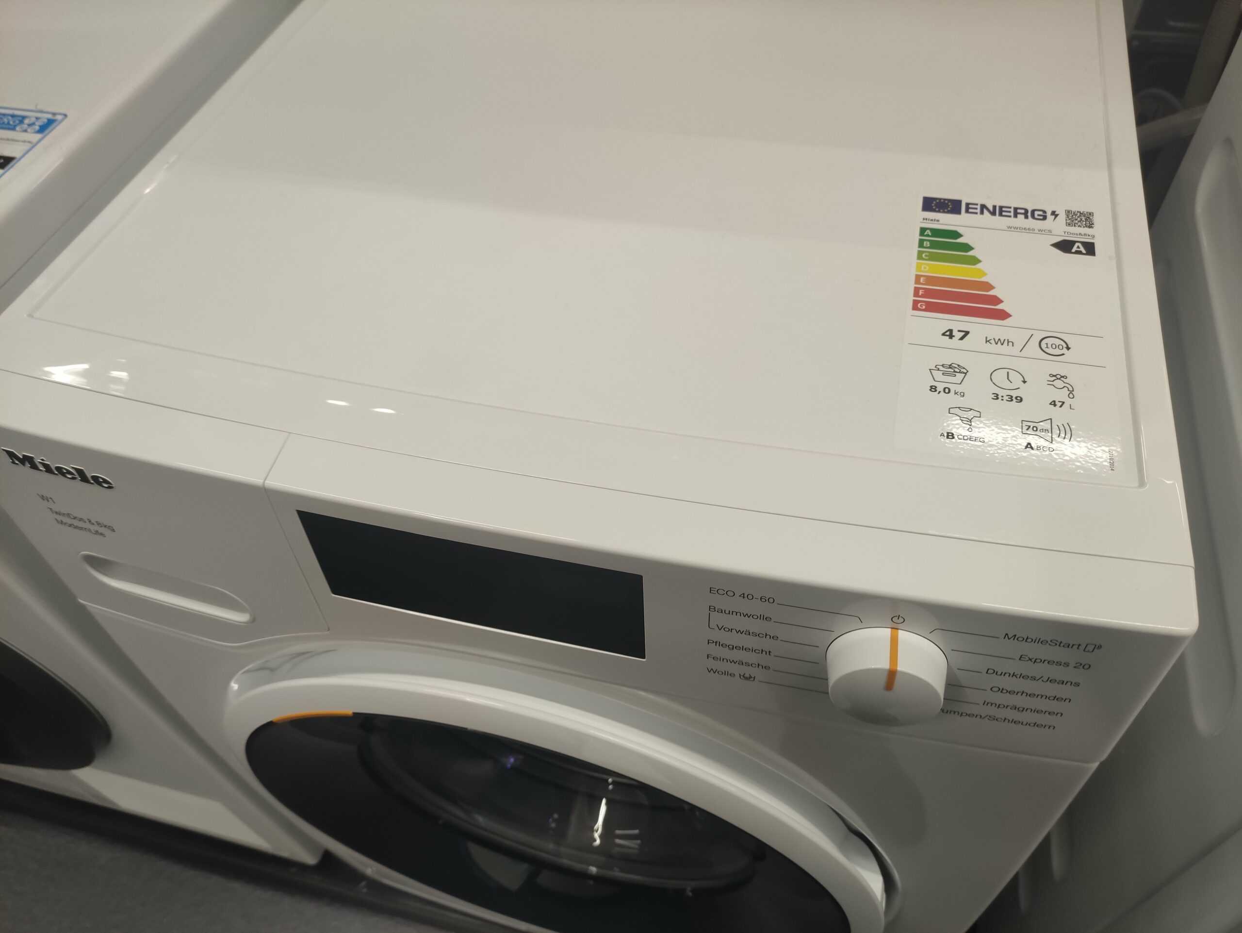 Weiße Waschmaschine mit Energieeffizienzlabel auf der Oberseite.