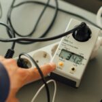 Strommessgerät steckt an einem Gerät und zeigt Werte an.