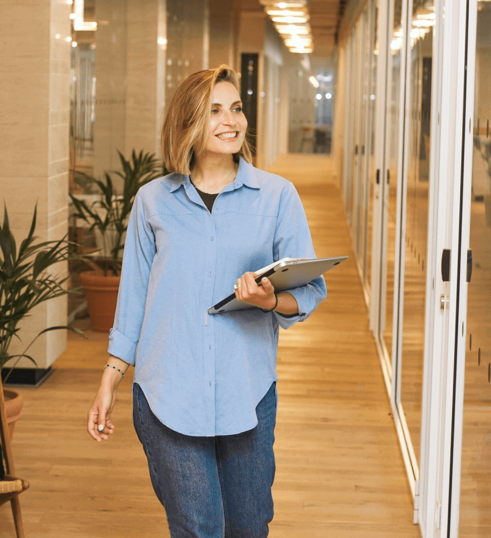 Frau geht mit Laptop im Büro spazieren.