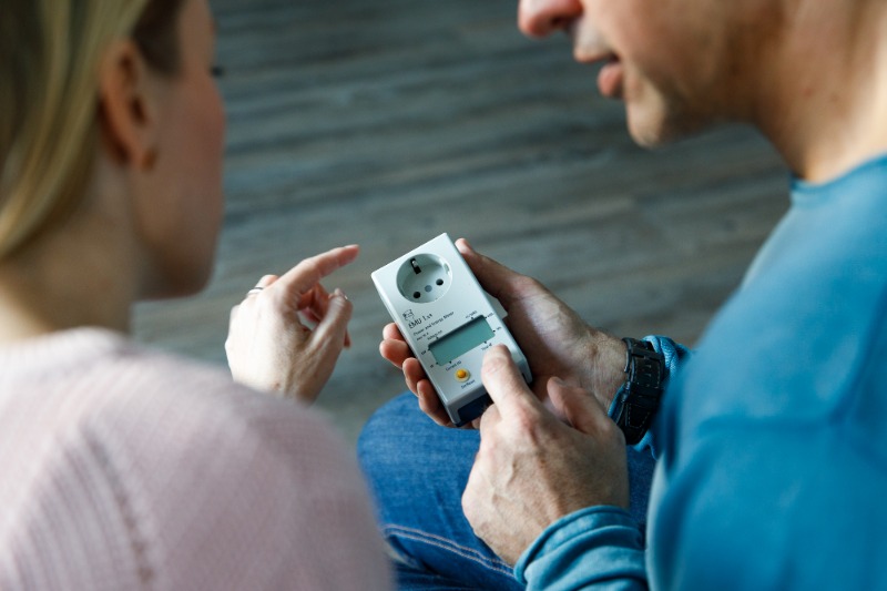 Frau und Mann bedienen Strommessgerät