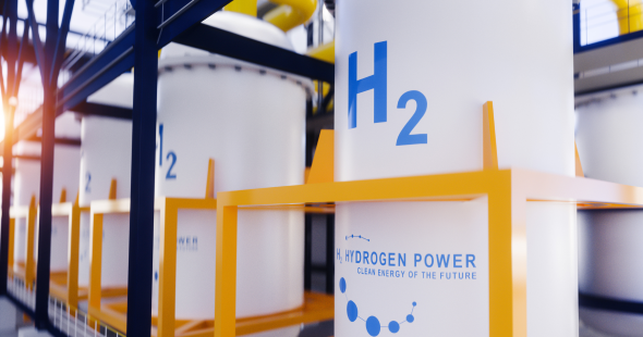 Wasserstoffspeichertanks mit der Aufschrift „H2“ durch Sonnenlicht, das durch eine Industrieanlage strömt.