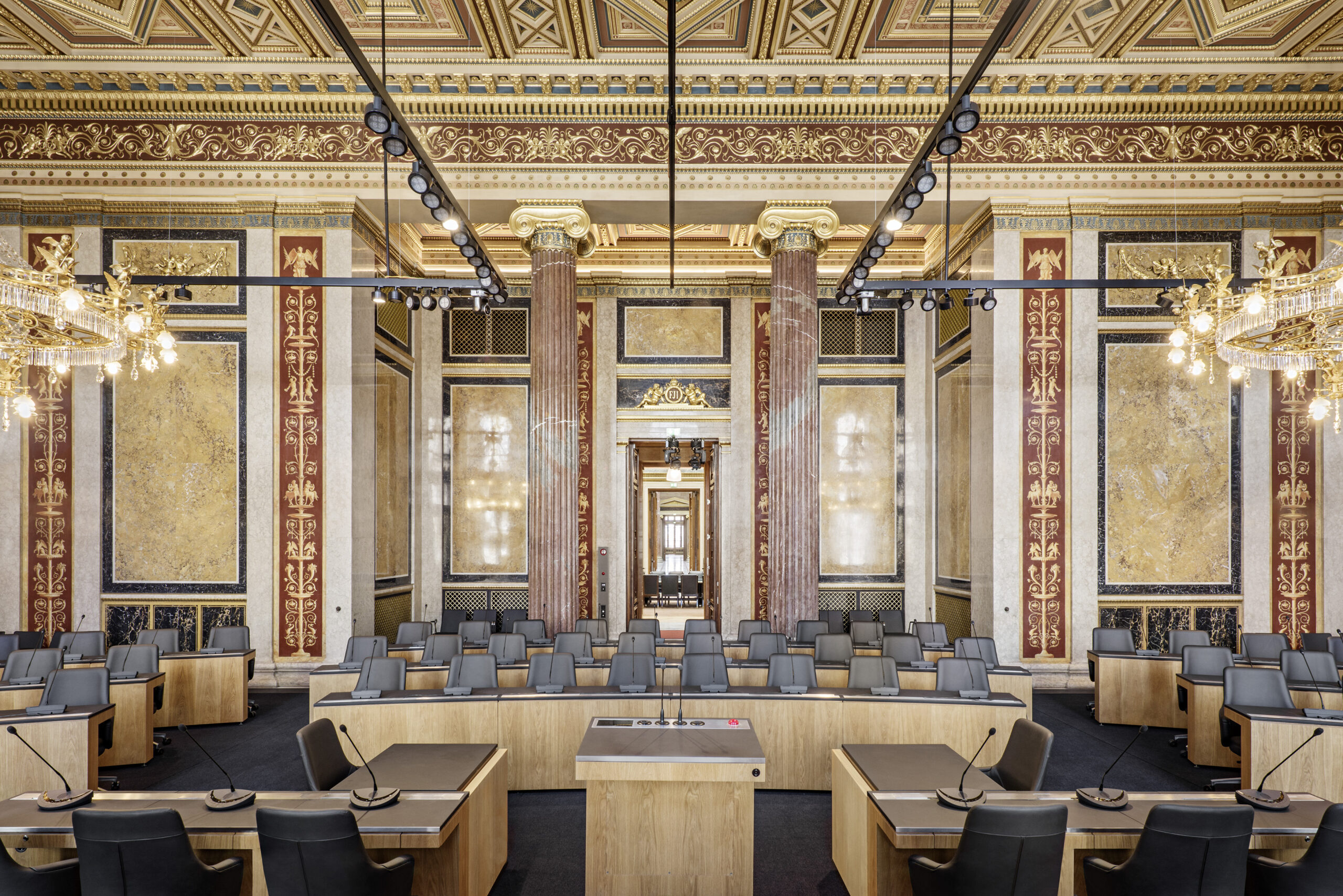 Der reich verzierte Bundesratssaal ist mit Holztischen, luxuriösen Kronleuchtern und einer dekorativen Decke und Wänden ausgestattet.