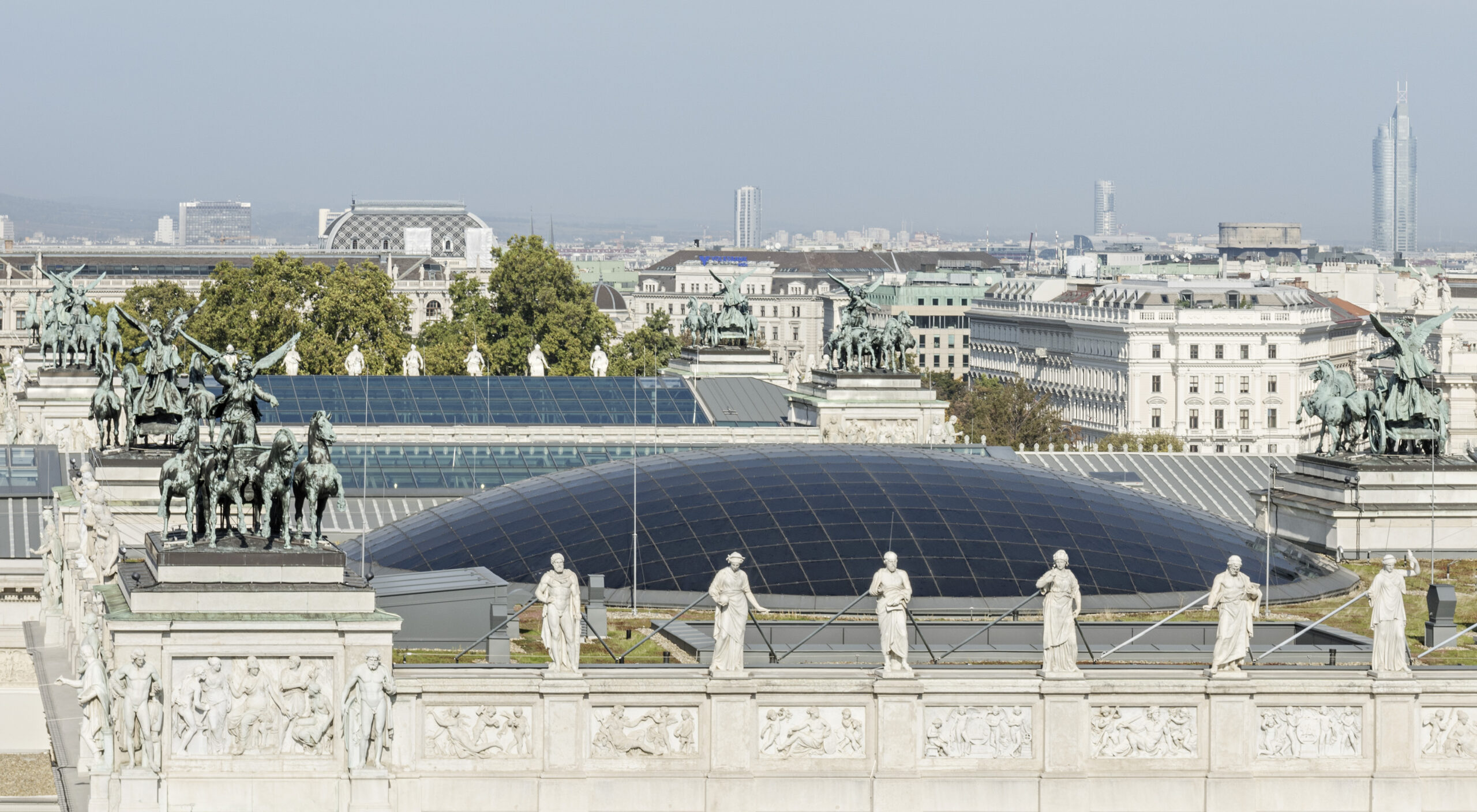 Vom Parlamentsdach aus überblicken Statuen die Skyline von Wien und präsentieren ein modernes Kuppelgebäude inmitten einer Mischung aus historischer und zeitgenössischer Architektur.