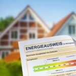 Im Hintergrund ist ein verschwommenes Haus zu sehen, im Vordergrund ist deutlich ein Energieausweis zu sehen.