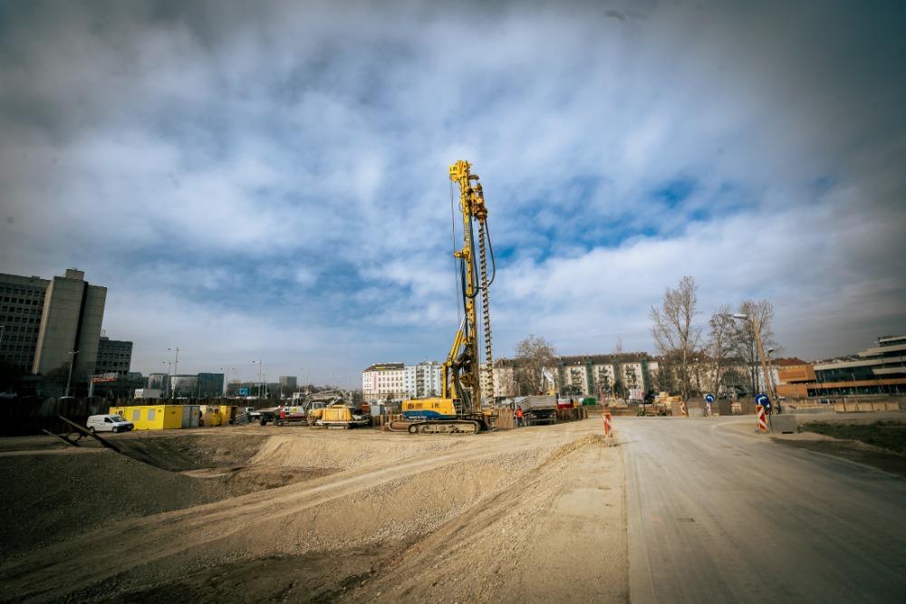Unter einem bewölkten Himmel steht eine Baustelle mit schweren Maschinen und riesigen Kränen, eingebettet zwischen Gebäuden und Feldwegen im Village im Dritten.