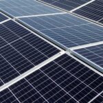 Nahaufnahme mehrerer reflektierender, gitterförmiger monokristalliner Photovoltaik-Module, die in einer Reihe angeordnet sind und Sonnenenergie nutzen.