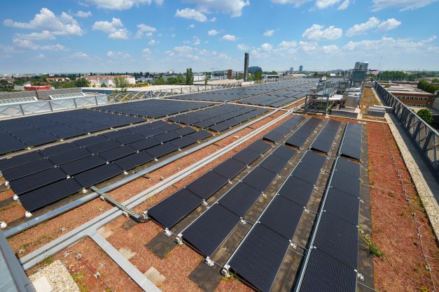Photovoltaikmodule auf dem Dach der Klinik Floridsdorf unter einem blauen Himmel mit vereinzelten Wolken.
