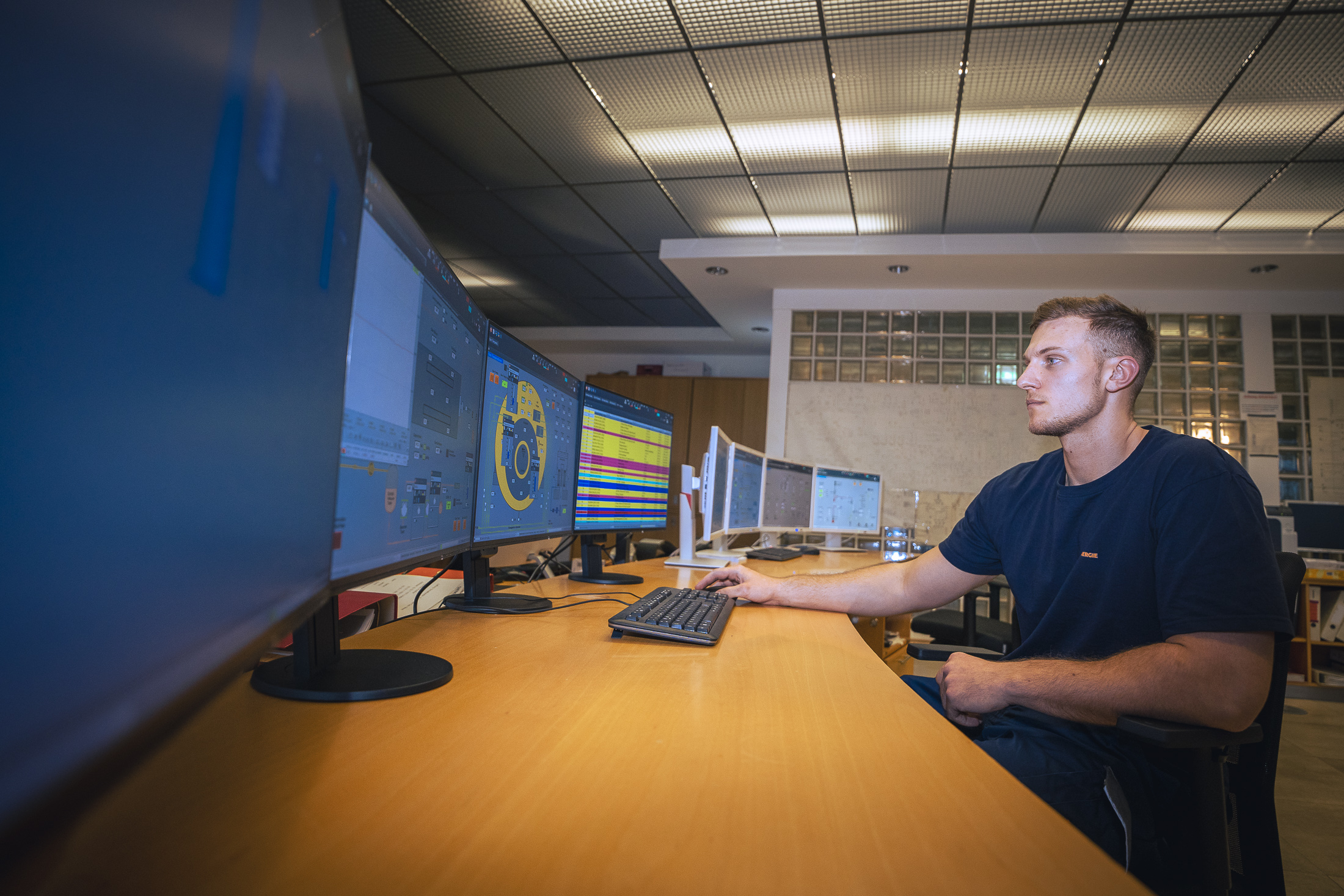 Jakob Königshofer arbeitet an einem Computertisch, der von mehreren Monitoren umgeben ist.