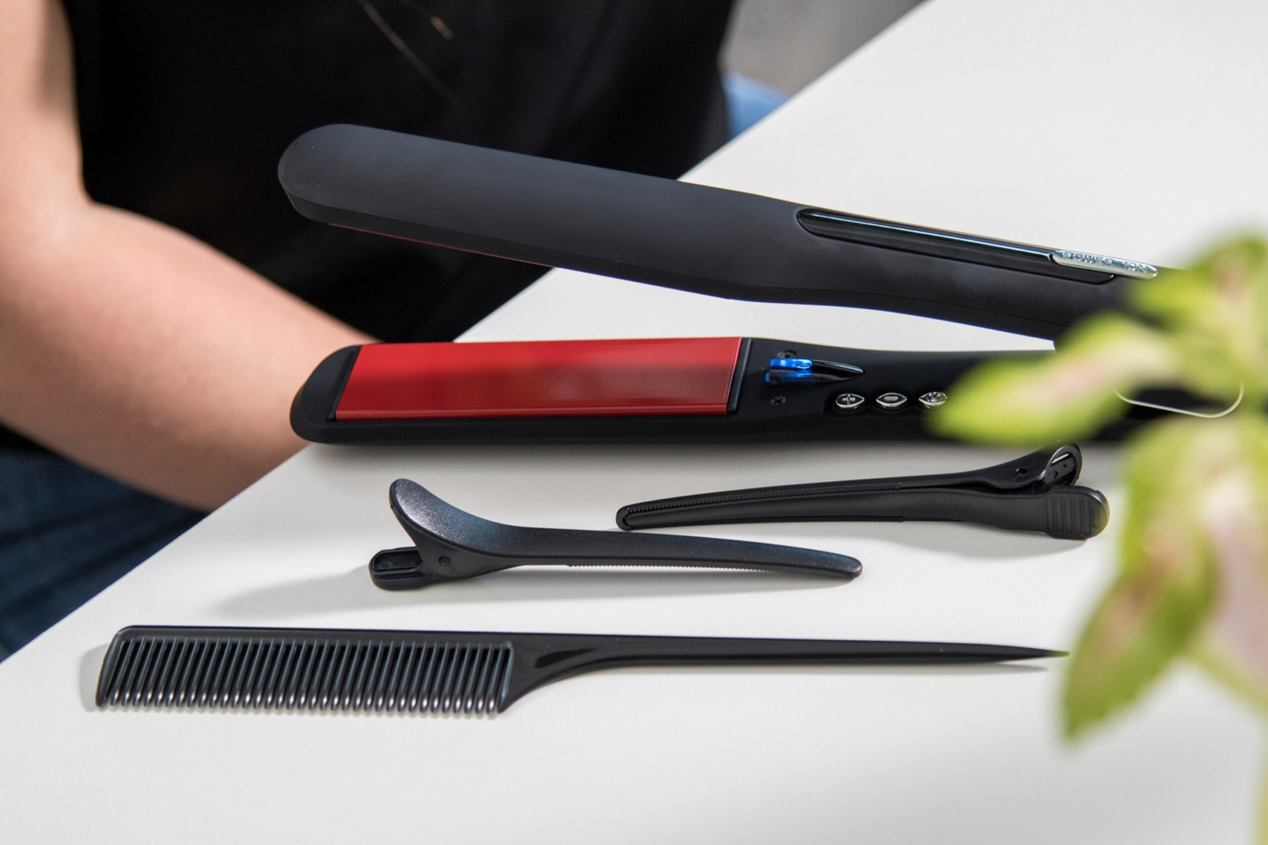 Ein schwarzes Glätteisen liegt auf deinem weißen Tisch.