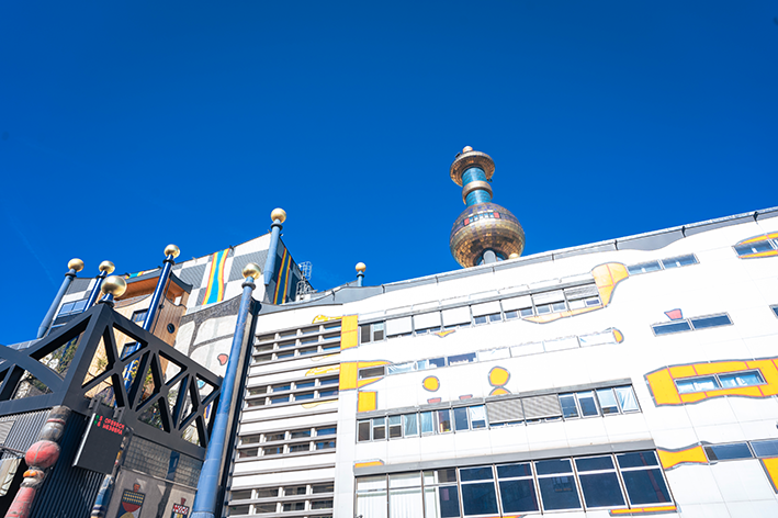 Farbenfrohes Industriegebäude mit einzigartiger Architektur unter einem klaren blauen Himmel. Außenansicht von der Abfallverwertungsanlage Spittelau.