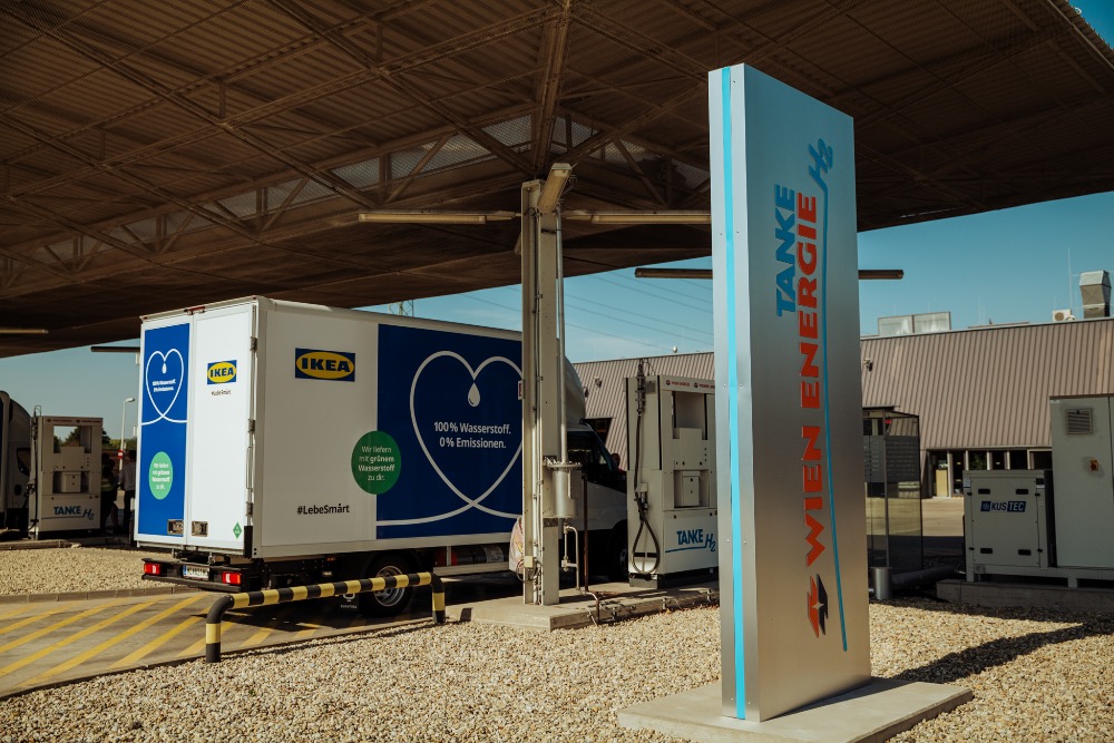 LKW an einer Ladestation Wien Energie Wasserstofftankstelle unter einem Vordach.