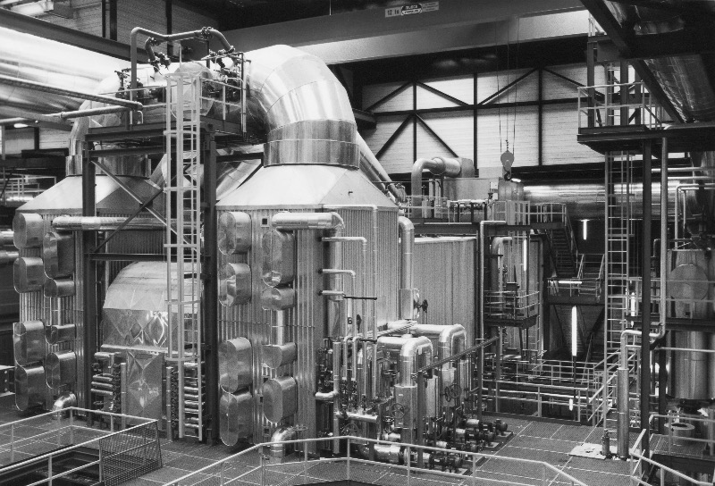 Das Heizkraftwerk ist geprägt von großen Maschinen, ineinander verschlungenen Rohren und hoch aufragenden Metallstrukturen.